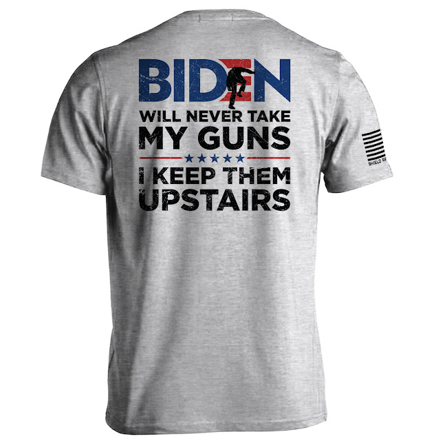 A grey t-shirt reads, "Biden will never take my guns. I keep them upstairs," with a silhouette of a gun. An American flag patch is on the sleeve.
