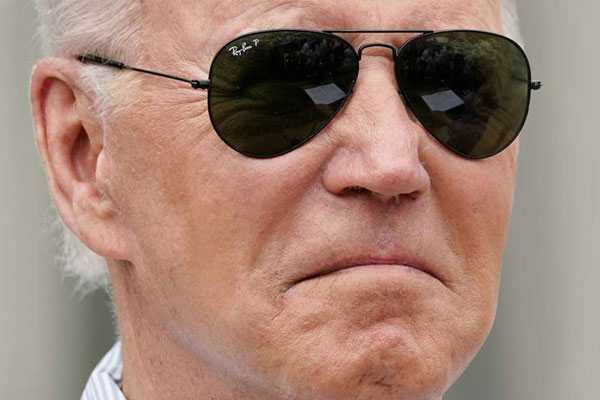 An older man with gray hair and wearing dark aviator sunglasses appears to be frowning slightly.