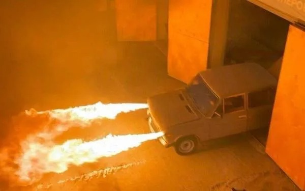 A car with flames coming out of the hood.