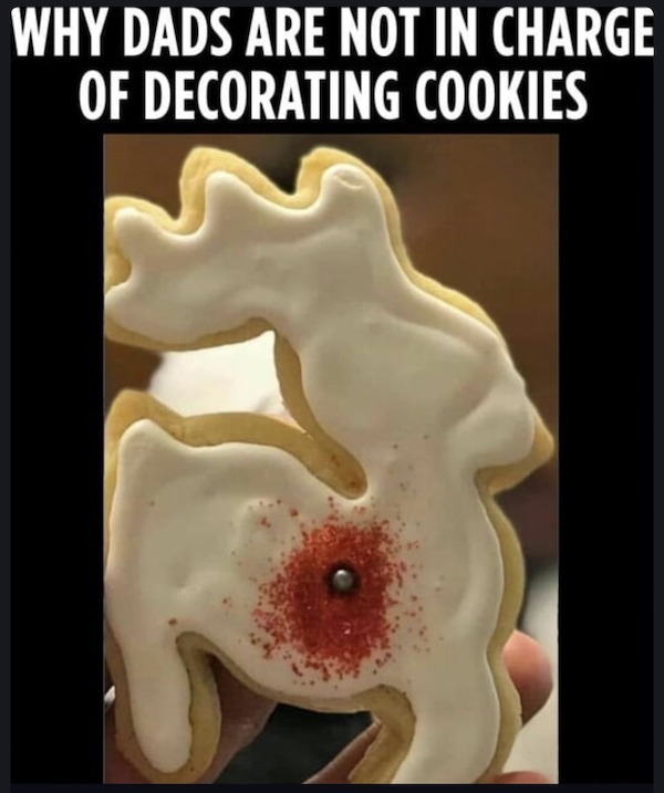 A poorly decorated reindeer-shaped cookie with white icing and red sprinkles, featuring a single candy, under the caption "Why dads are not in charge of decorating cookies.