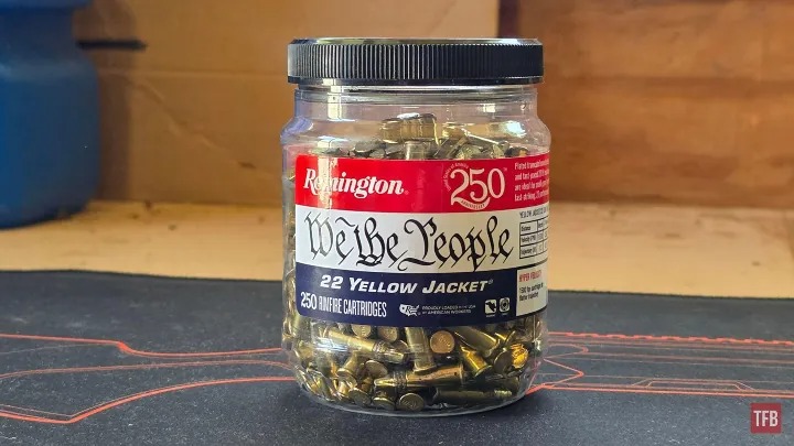 A plastic jar labeled "Remington We The People .22 Yellow Jacket" contains 250 rimfire cartridges, displayed on a work surface.